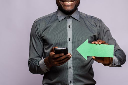 A happy black man holding phone and arrow pointing to it