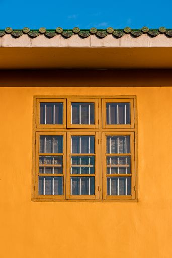 A vertical shot of an old painted window of an orange building on a sunny day in summer