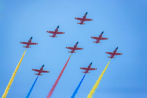 A low-angle shot of Military aviation in the blue sky with colorful smoke