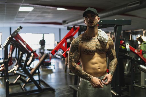 A handsome tattooed Caucasian man in a cap working out at the gym