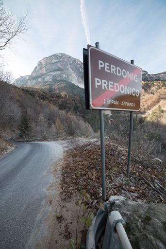 A vertical shot of a road in mountains with a street sign