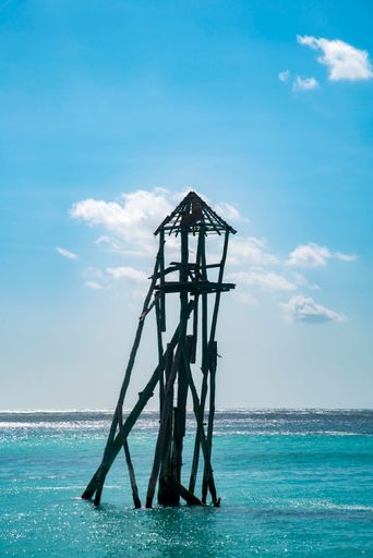 A vertical shot of an old wooden damaged wooden tower on the beach in Cancun, Mexico