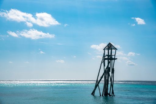 An old wooden damaged wooden tower against a blue cloudy sky on the beach in Cancun, Mexico