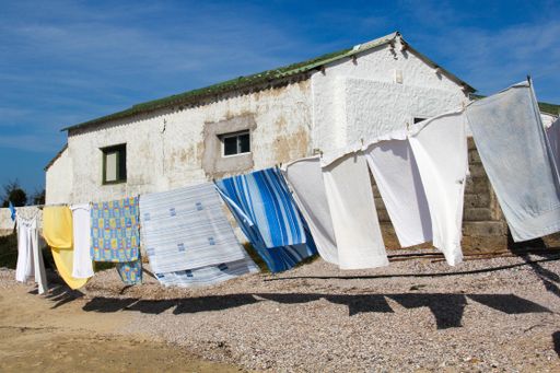 The clothes hanging from the clothesline with an old building on the background in the countryside