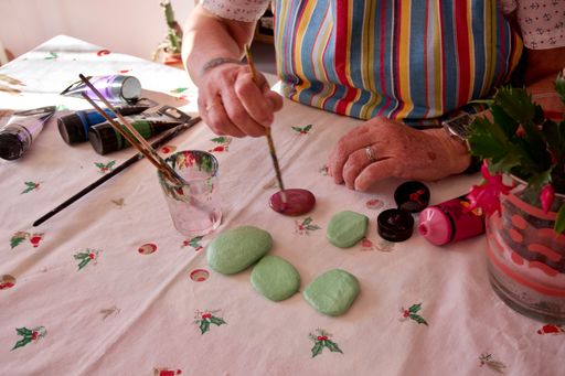 A close-up shot of a Caucasian woman painting some flat stones with acrylic.