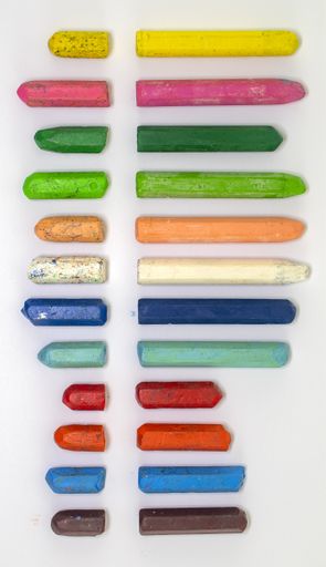 A vertical shot of colorful broken crayons isolated on a grey background