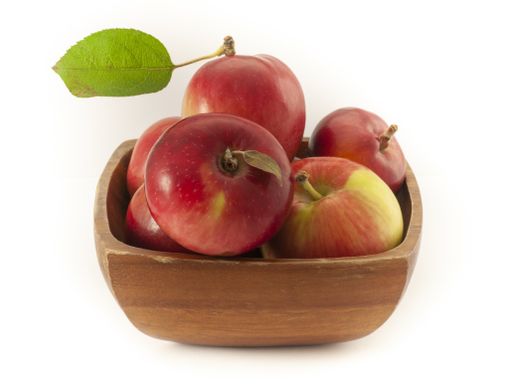 A closeup shot of red apples in a wooden bowl isolated on a white background