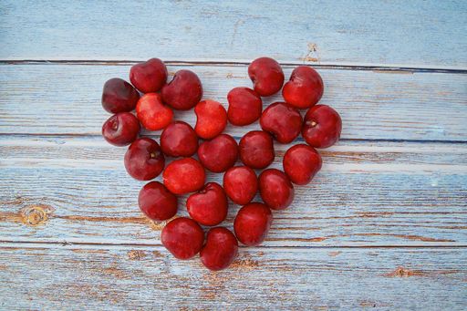 A closeup shot of heart-shaped juicy cherries on wooden background