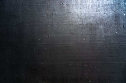 A closeup shot of a metallic black surface reflecting light - suitable as a cool and dramatic background