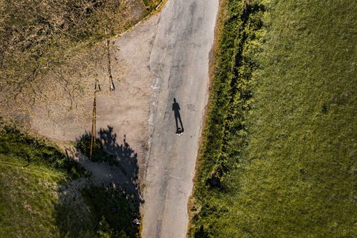 An aerial shot of a person standing in the middle of the road surrounded with greenery