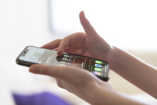 A selective focus shot of the female holding her smartphone and reading news