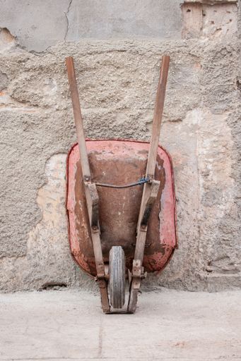 A vertical shot of a construction trolley leaning on a concrete wall