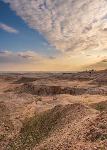 A landscape view of a desert under a blue cloudy sky during the sunset