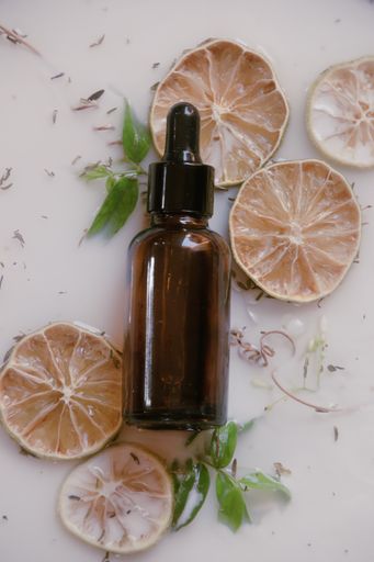 A vertical top view of a glass dropper of natural anti aging serum with dried lemons on the table