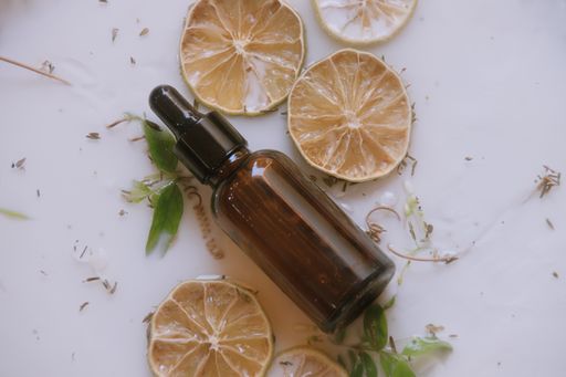A top view of a glass dropper of natural anti aging serum with dried lemons on the table