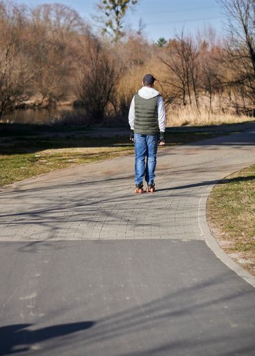 A vertical shot of a male riding on roller skates on a sunny day in Wartostrada, Poznan, Poland