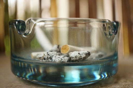 A closeup shot of a glass  ashtray with cigarette bulls