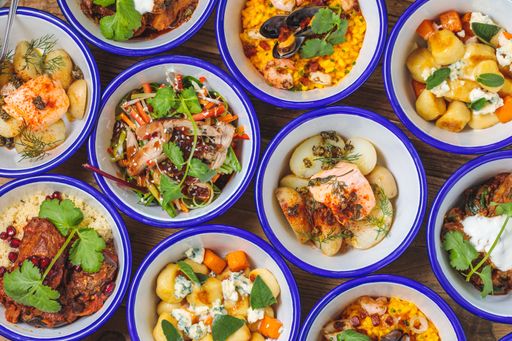 An overhead shot of different types of dishes in bowls near each other on a wooden surface