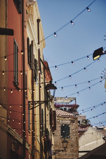A low angle shot of hanging lights and colorful buildings in Alghero Old town in Northern Sardinia, Italy