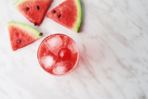 A high angle shot of a red drink near watermelon slices