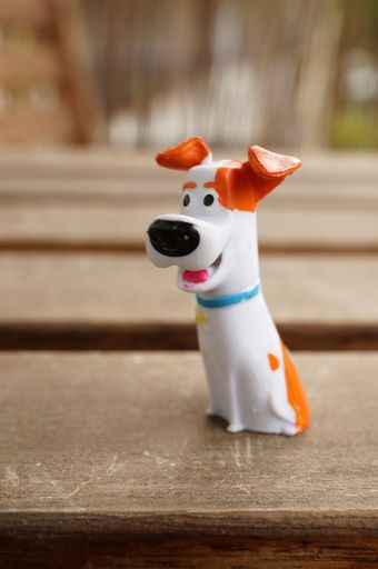Plastic toy Max dog figurine from the Secret Life Of Pets movie on a wooden surface