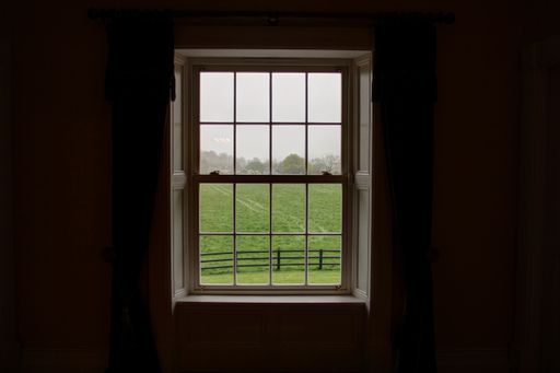 A window in a dark room with a  beautiful view of the field