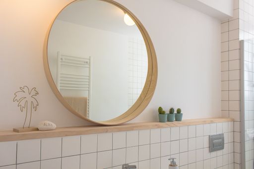 A beautiful shot of a mirror of the bathroom with wooden frame near three decorative plants in blue pots