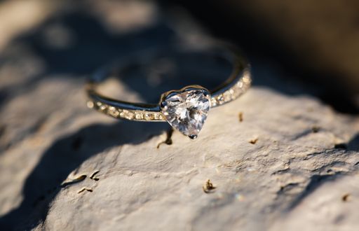 A selective closeup shot of a heart-shaped ring on a rock with a blurred background