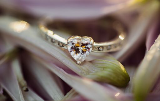 A selective closeup focus shot of a heart-shaped diamond ring on a flower with a blurred background