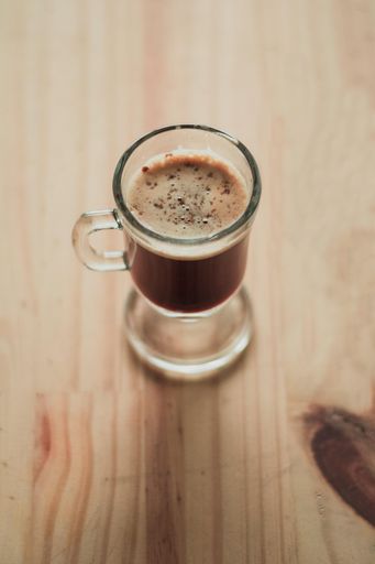 A high angle shot of a cup of Cappucino on a wooden surface