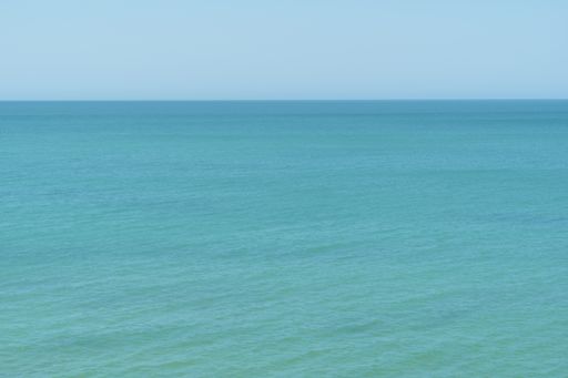 An aerial shot of a turquoise seascape under sunlight