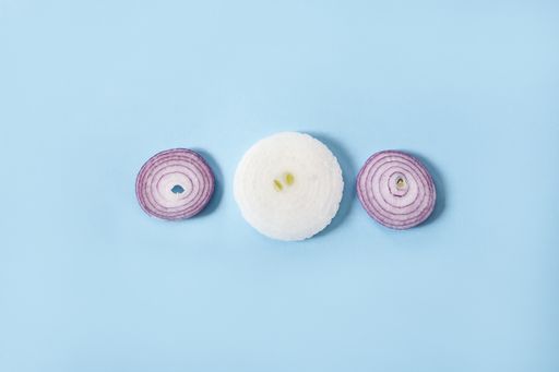 An overhead shot of slices of onions on a blue background