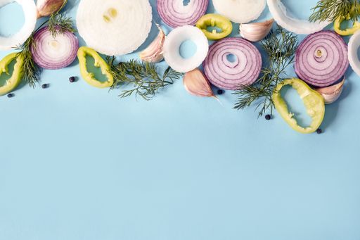 An overhead shot of slices of different vegetables on a blue background