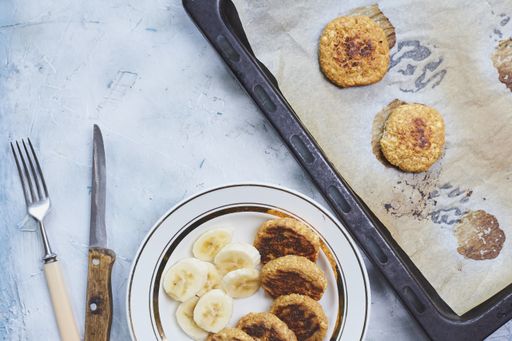 A top view of healthy meal made of banana slices and freshly baked oatmeal patties with knife and fork