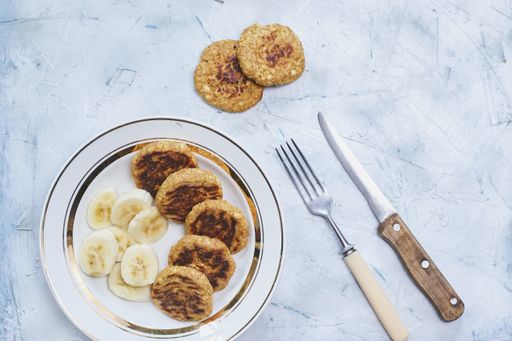 A top view of healthy meal made of banana slices and freshly baked oatmeal patties with knife and fork