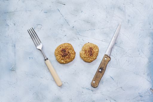 An overhead shot of two banana cookies between the knife and fork on the table