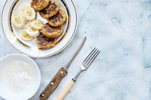 White cream, fork and a knife next to bananas and cookies