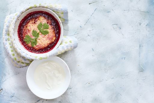 An overhead shot of a salad with mashed potatoes, tomato, and white sauce
