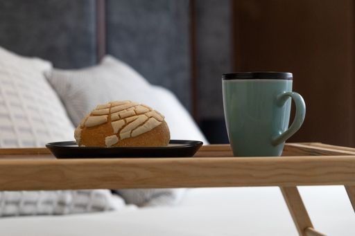 A closeup shot of a coffee and sweet bread on a bedside table