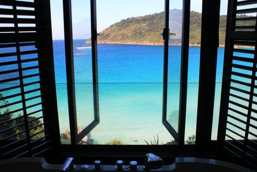 A beautiful view of blue seawater seen from an open window of a building