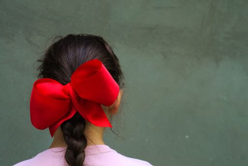 A young Siberian girl with a red ribbon on its braided hair isolated on a gray background  - hairstyle concept