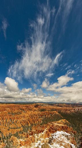 A vertical high angle view of the crimson-colored hoodoos under the cloudy sky in the Bryce Canyon National Park, Utah, USA