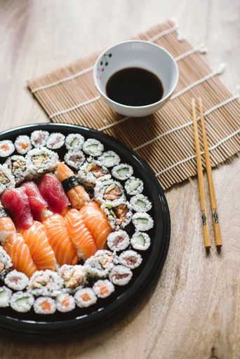 A selective focus shot of the delicious sushi rolls served in a black round plate