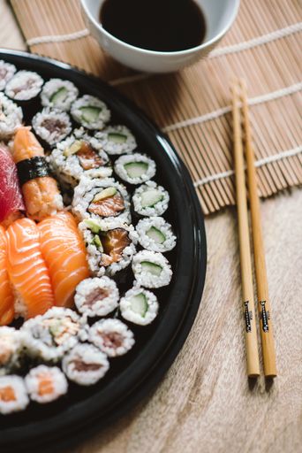 A selective focus shot of the delicious sushi rolls served in a black round plate