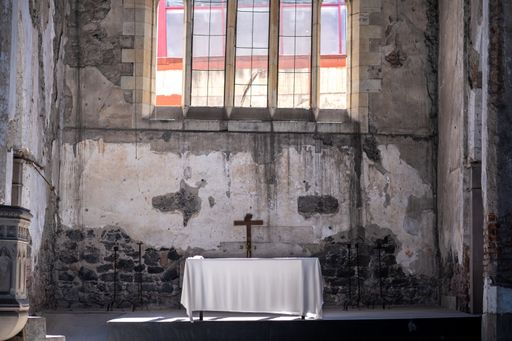 An abandoned church with a small table and cross inside the building