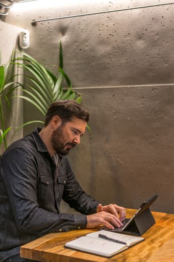 A vertical shot of a young caucasian bearded male working on a tablet
