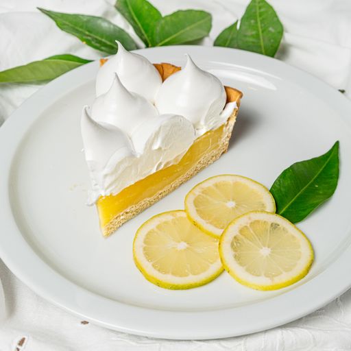 A piece of lemon cake with a mousse topping in a plate under the lights