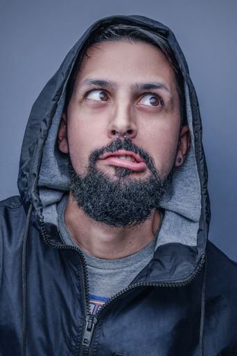 A vertical shot of a bearded male making a funny face at the camera isolated on a gray background