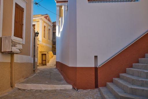 A horizontal shot of grey staircases near the white and red building and a pathway leading to the yellow house
