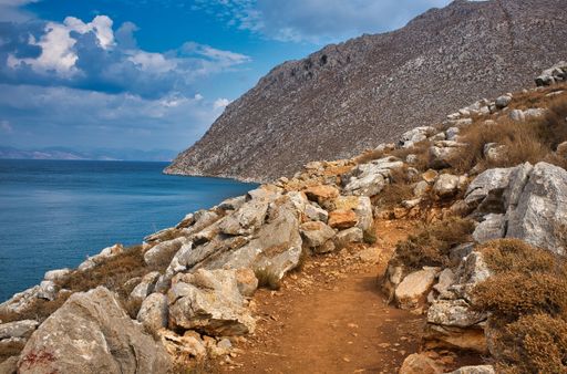 A wide shot of rocky mountain range near the sea under the beautiful cloudy sky in Symi, Greece